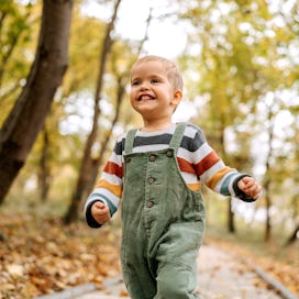 Portrait of cute little smiling boy running in a public park
