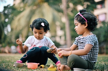 两个蹒跚学步的女孩在花园里玩她们的厨万博体育app安卓版下载房用具