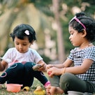 Two Toddler girls playing with their kitchen set in the garden