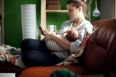 Middle-aged mother plus size feeds newborn and looks at screen of smartphone. So tired mother.