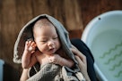 高角度拍摄，一位慈爱的亚洲母亲抱着用毛巾裹着的新生婴儿，给女婴擦干…