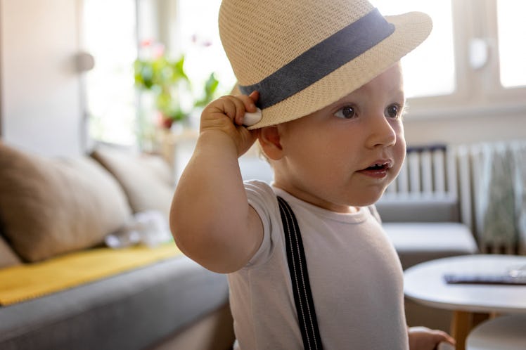 Baby boy wearing a hat and suspenders and being playful