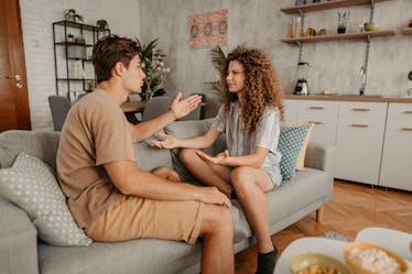 Young couple with relationship problems, sitting on the sofa in the living room and arguing.