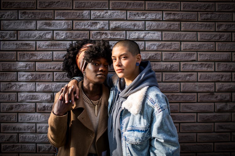 a young couple poses for a photo in front of a brick wall, as they consider which zodiac signs will ...