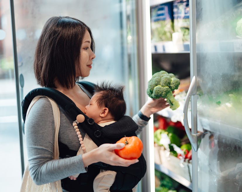 Young Asian mother doing grocery shopping with her baby in organic supermarket. Healthy and balanced...