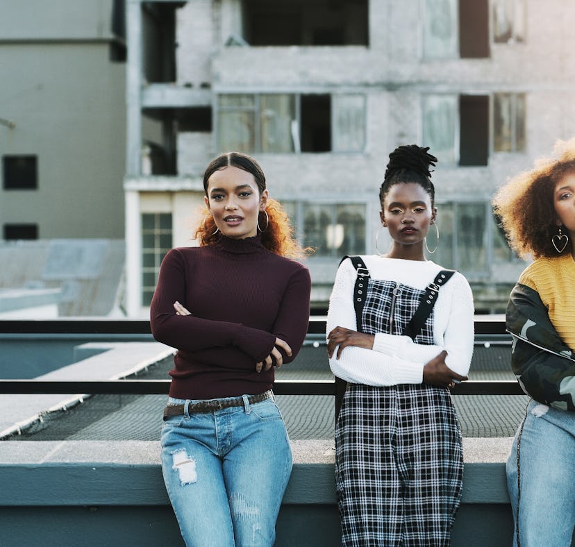 three friends relax on a rooftop and pose with serious expressions, as they consider how christmas 2...