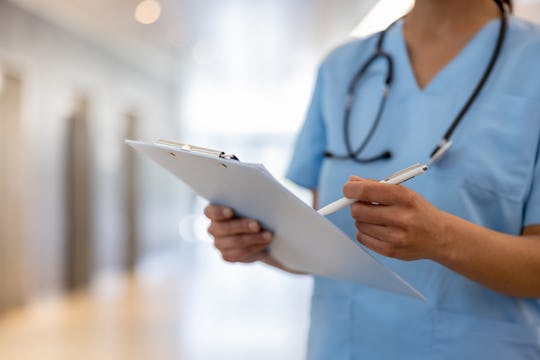 Close-up on a nurse holding a clipboard and writing on a medical chart at the hospital - healthcare ...