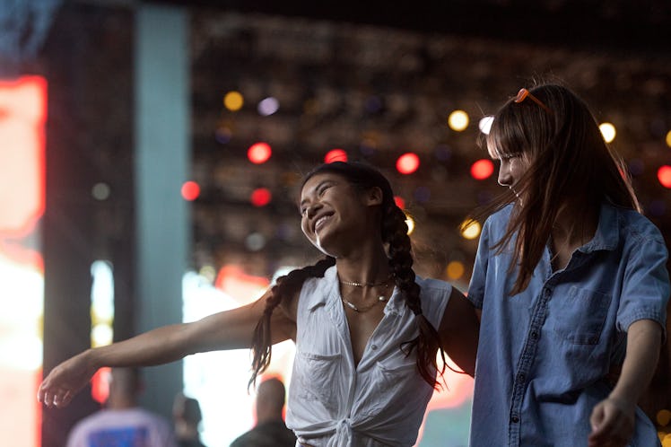Two girlfriends of Asian and Caucasian ethnicity are dancing in front of the stage and enjoying the ...