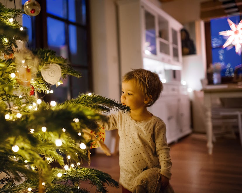 A little boy marvels at the Christmas tree, lit up on Christmas Eve.