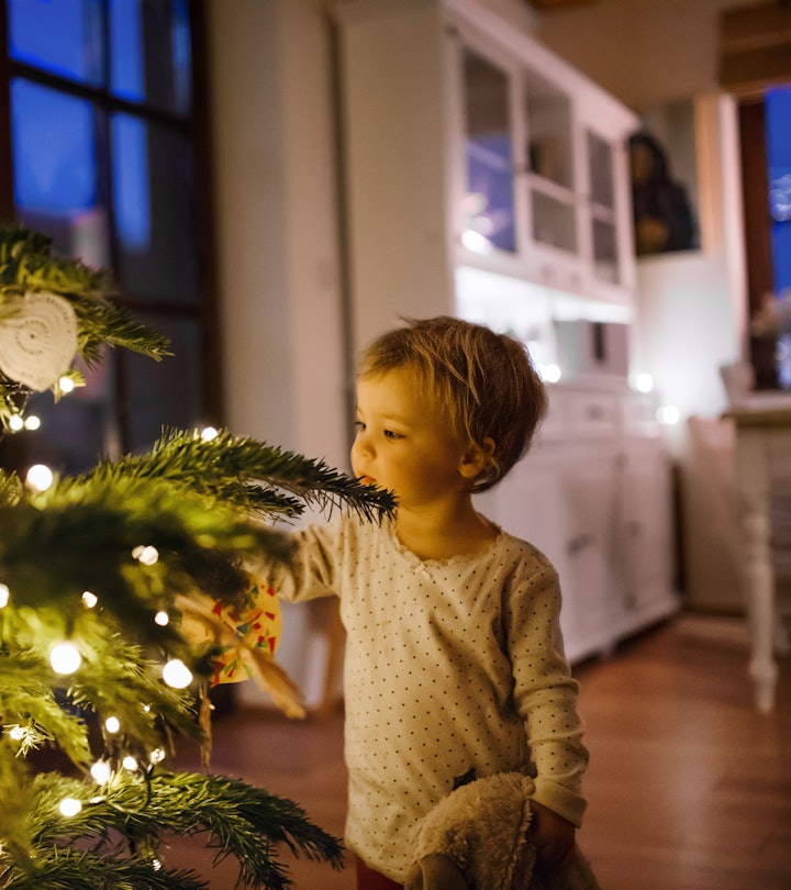 A little boy marvels at the Christmas tree, lit up on Christmas Eve.
