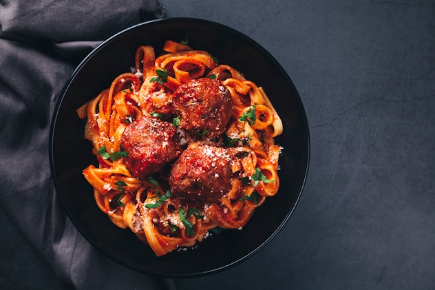 Flat lay of tagliatelle  with meatballs and  tomato sauce on black background. funny names for priva...