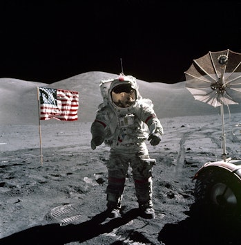 This is an Apollo 17 Astronaut standing upon the lunar surface with the United States flag in the ba...