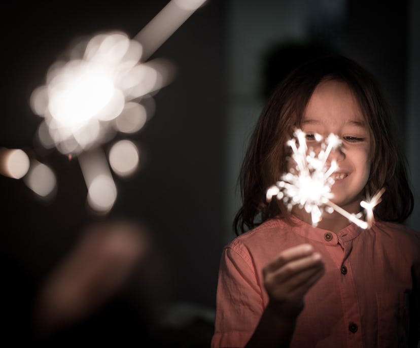 Kid with sparkler for New Year , host a party at home to celebrate new years eve with kids