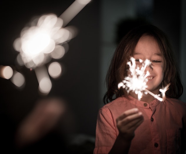 Kid with sparkler for New Year , host a party at home to celebrate new years eve with kids