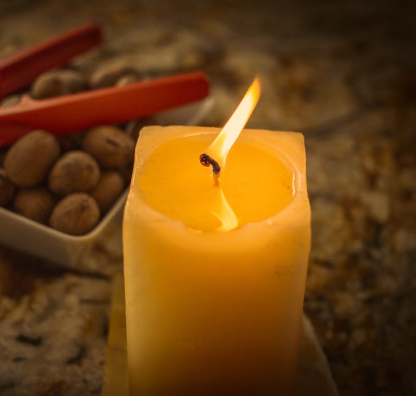 A butter candle from TikTok sits on a table next to some olives.