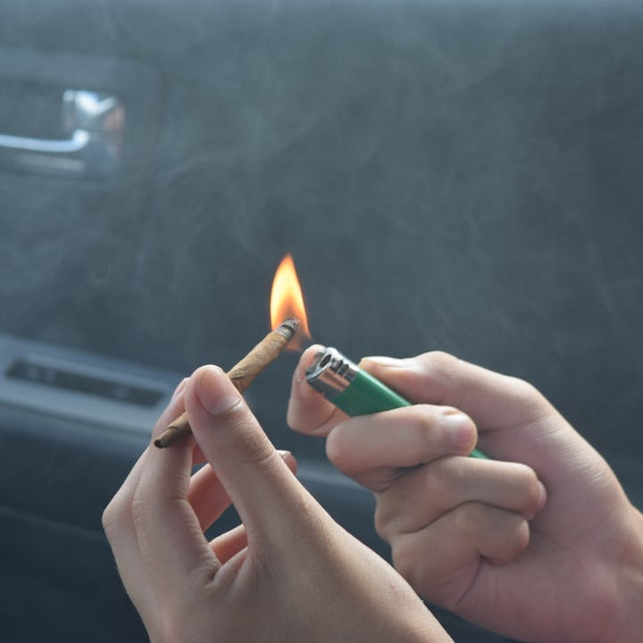 Hands lighting a cannabis joint in the car. Massachusetts is set to become the first state to introd...