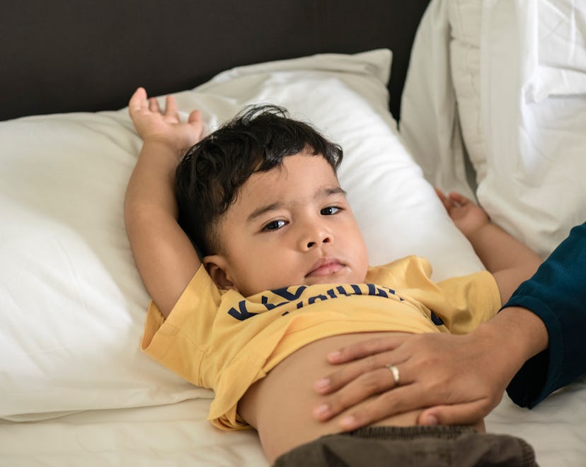 toddler lying in bed with stomach pain, home remedies for stomach pain in kids