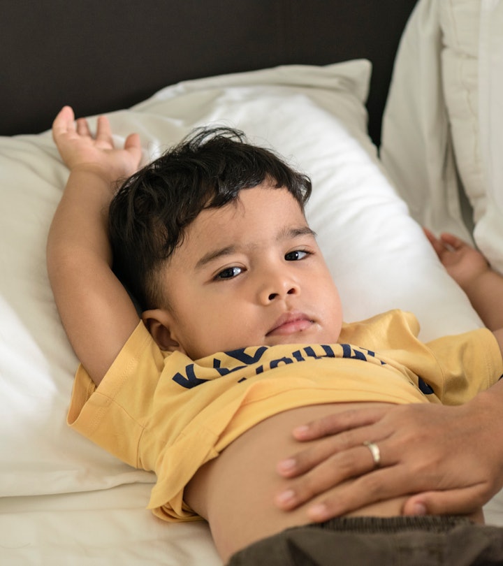 toddler lying in bed with stomach pain, home remedies for stomach pain in kids