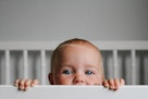 一个婴儿的肖像从她的婴儿床的栅栏偷看。