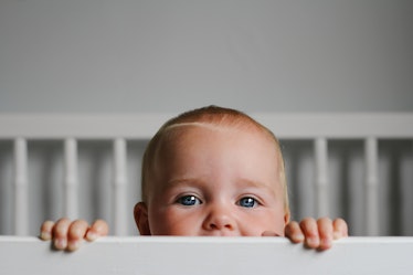 一个婴儿的肖像从她的婴儿床的栅栏偷看。