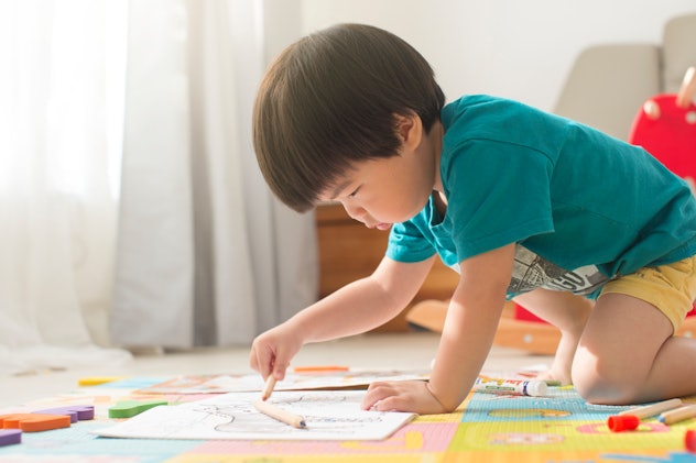 Baby boy learns to color with crayons on the floor, in a story about Capricorn baby traits and Capri...