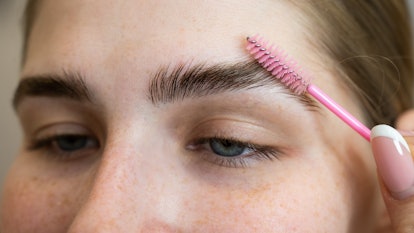 A woman applying an eyebrow serum.