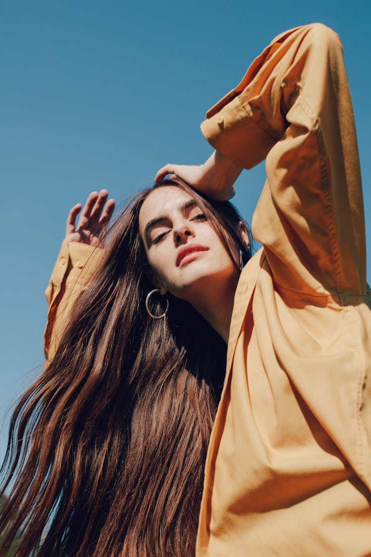 young woman in oversized blazer gazes into camera as she considers the spiritual meaning of the dece...