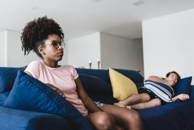 Couple of teenage friends sitting on sofa in living room
