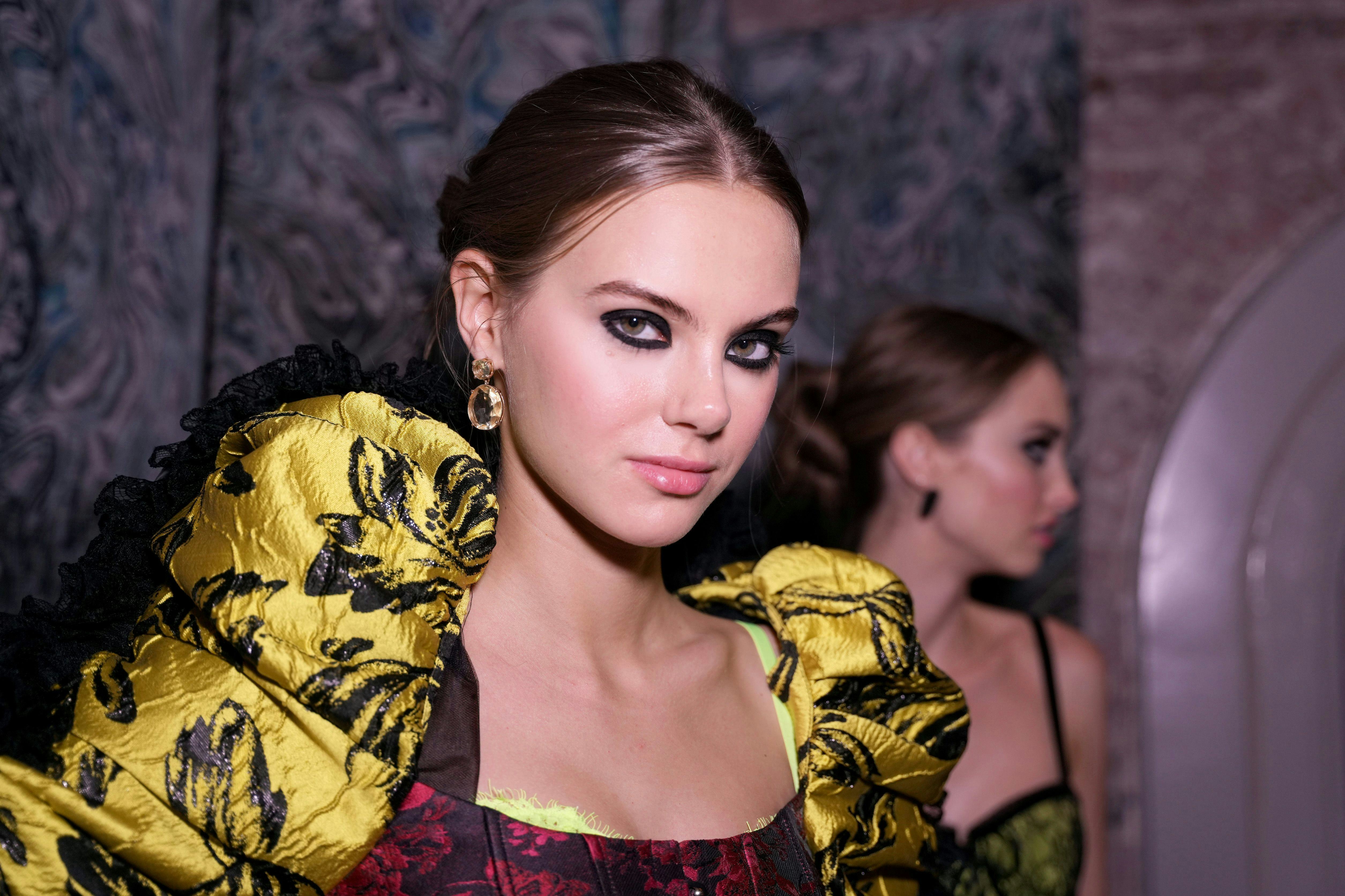 A model poses during the Alice + Olivia by Stacey Bendet Fall 2022 Presentation wearing smudgy black...