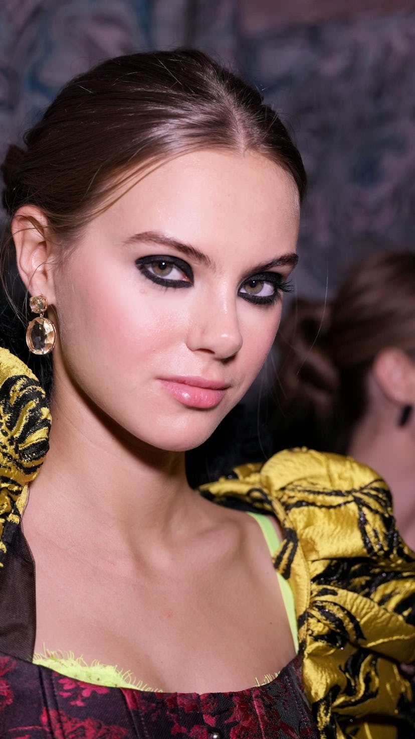 A model poses during the Alice + Olivia by Stacey Bendet Fall 2022 Presentation wearing smudgy black...