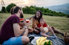 快乐的多元家庭，两个孩子坐在野餐毯上，弹吉他唱歌万博体育app安卓版下载