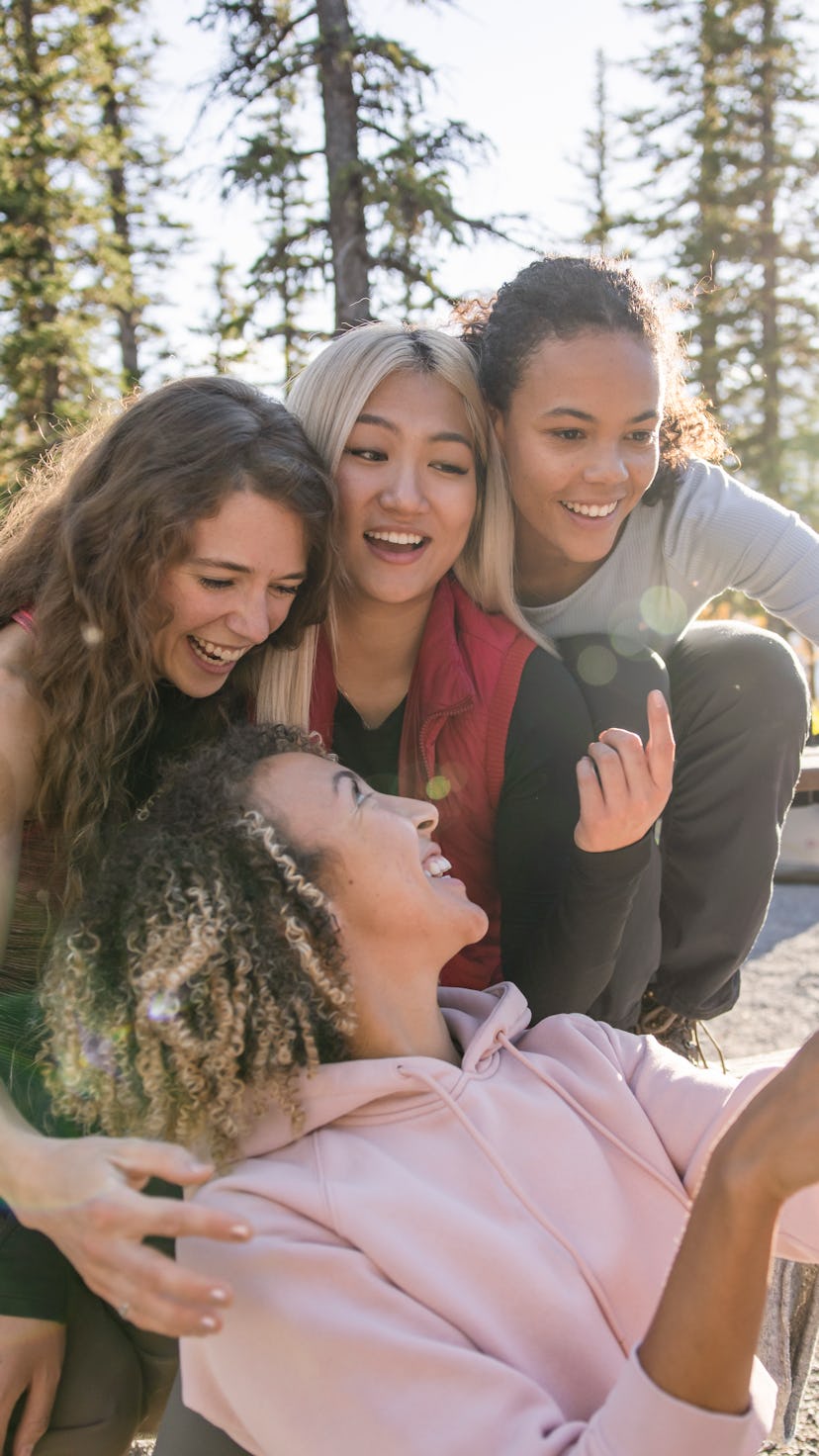 Happy, carefree young women friends taking selfie at sunny campsite in woods