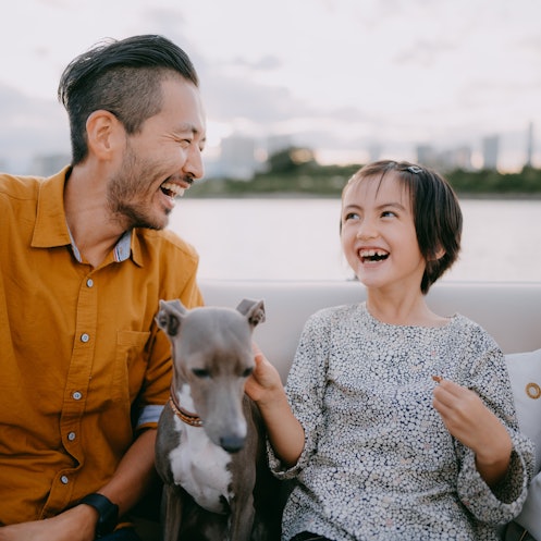 日本东京湾，父亲和小女儿在船上和狗狗玩得很开心