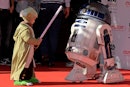 科隆，德国——5月20日:一个打扮成尤达大师的小男孩在公园里遇见了R2-D2模型。