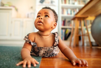 Baby girl crawling around on the living room floor of her home, in a story about baby name trends fo...