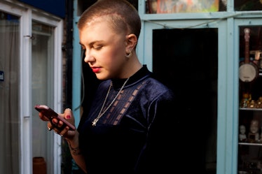 a young woman looks at her phone as she considers how 2022's last mercury retrograde might affect he...