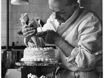 A confectioner at a Knightsbridge store pipes the finishing touches onto cakes which will be in the ...