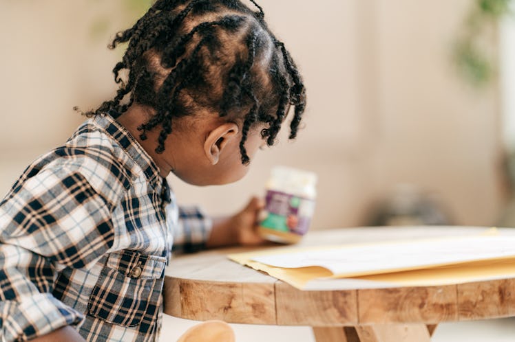 A toddler sitting at a table, staring at a jar.