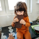 一个孩子正在咬一块巨大的巧克力棒。