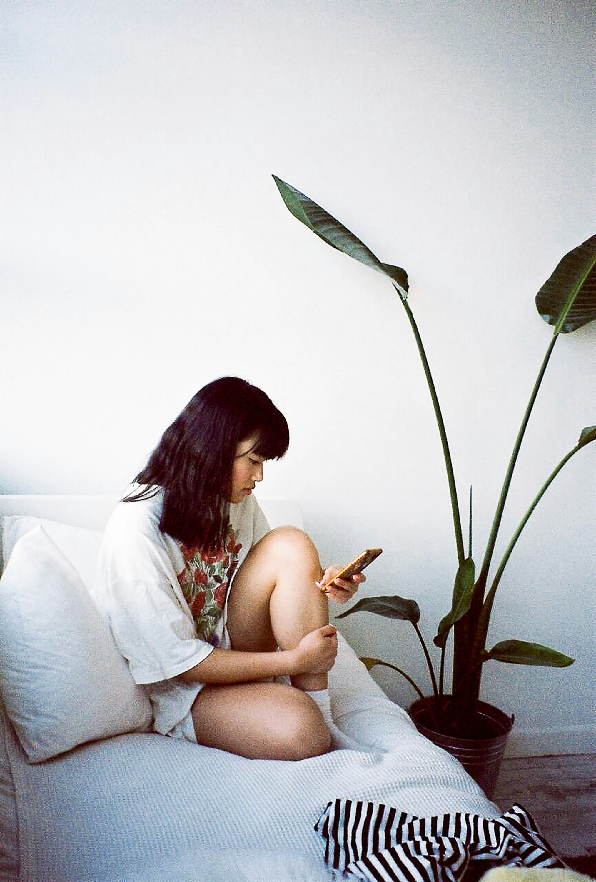 Young woman holding her knee on the couch during 2022's last Mercury retrograde, which will affect h...