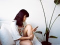 Young woman holding her knee on the couch during 2022's last Mercury retrograde, which will affect h...