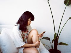 Young woman holding her knee on the couch during 2022's last Mercury retrograde, which will affect h...