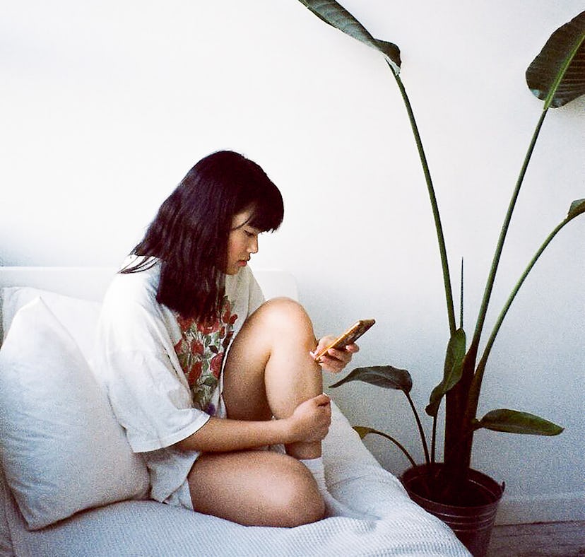 Young woman holding her knee on the couch during 2022's last Mercury retrograde, which will affect h...