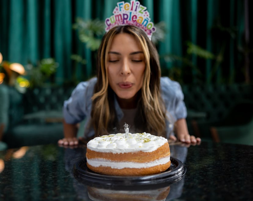 Happy woman celebrating her birthday and blowing out the candles on her cake