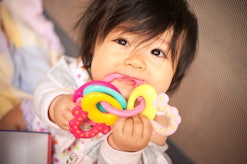  a baby chewing on a teether in an article about teething fever