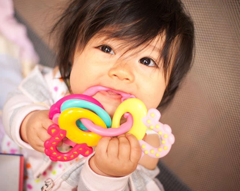  a baby chewing on a teether in an article about teething fever