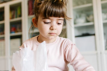 Beautiful and cute girl looking down. She is picking up cereal after her brother has thrown them on ...