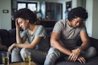 年轻的黑人夫妇在家里的沙发上争吵后感到悲伤。