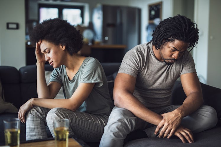 Young black couple feeling sad after arguing on sofa at home.