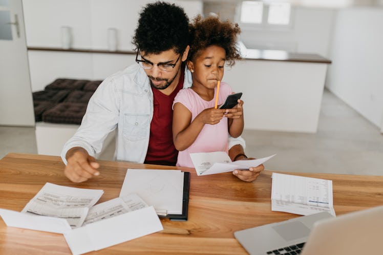 Father and daughter at apartment, domestic room, crowded with bills to pay. Man with his child is do...